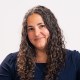 a woman with long curly hair is smiling.