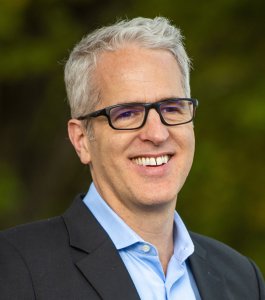 A man wearing glasses and a blue shirt.