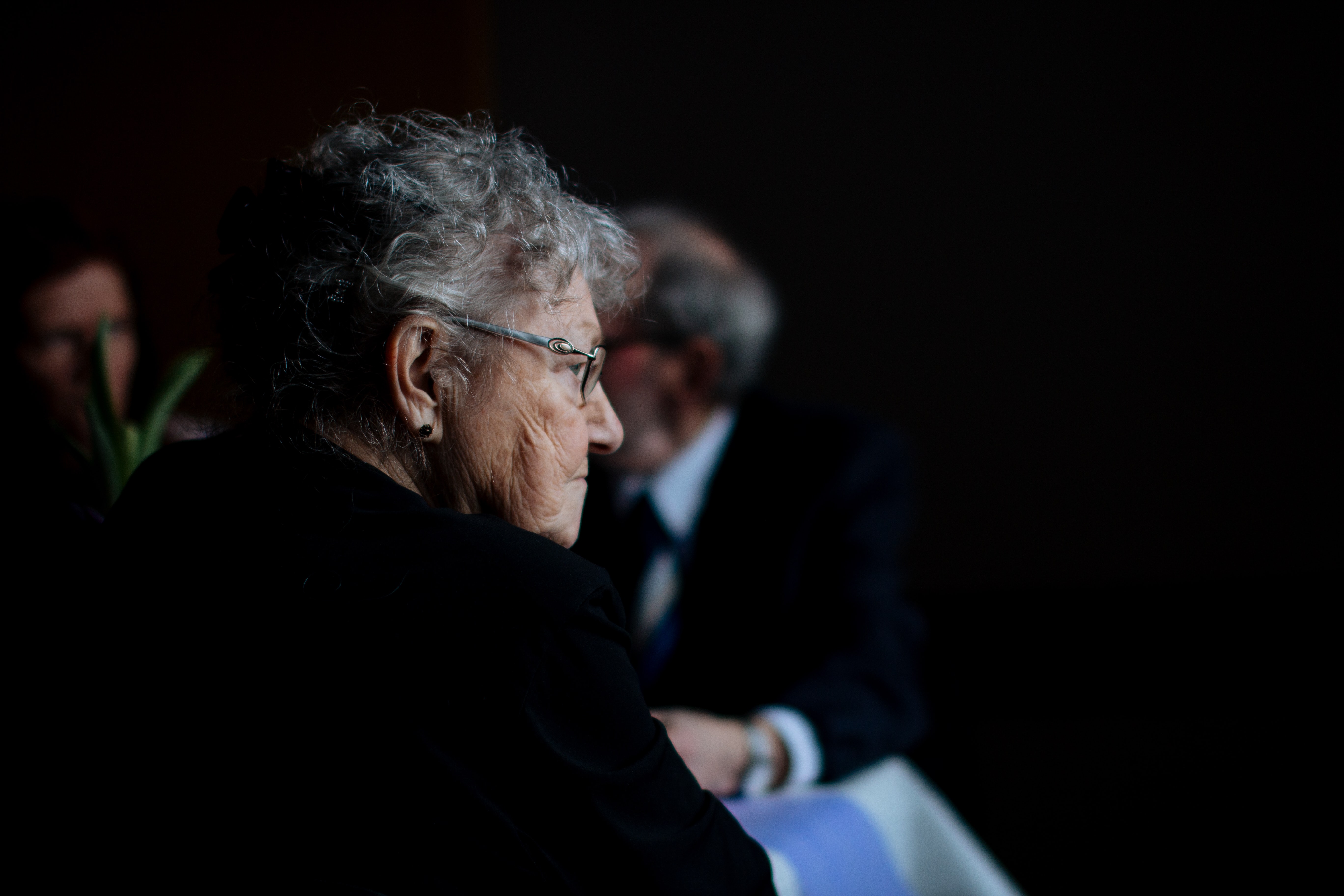 an older woman against a dark background illustrating aging loneliness and regret