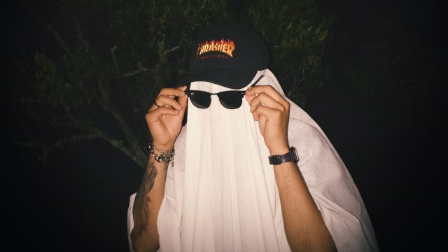 A man in a ghost costume showing why Halloween is so popular for adults.