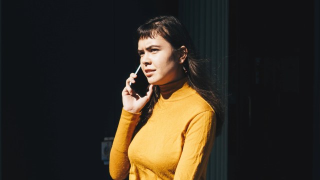 A woman in a yellow shirt talking on the phone.