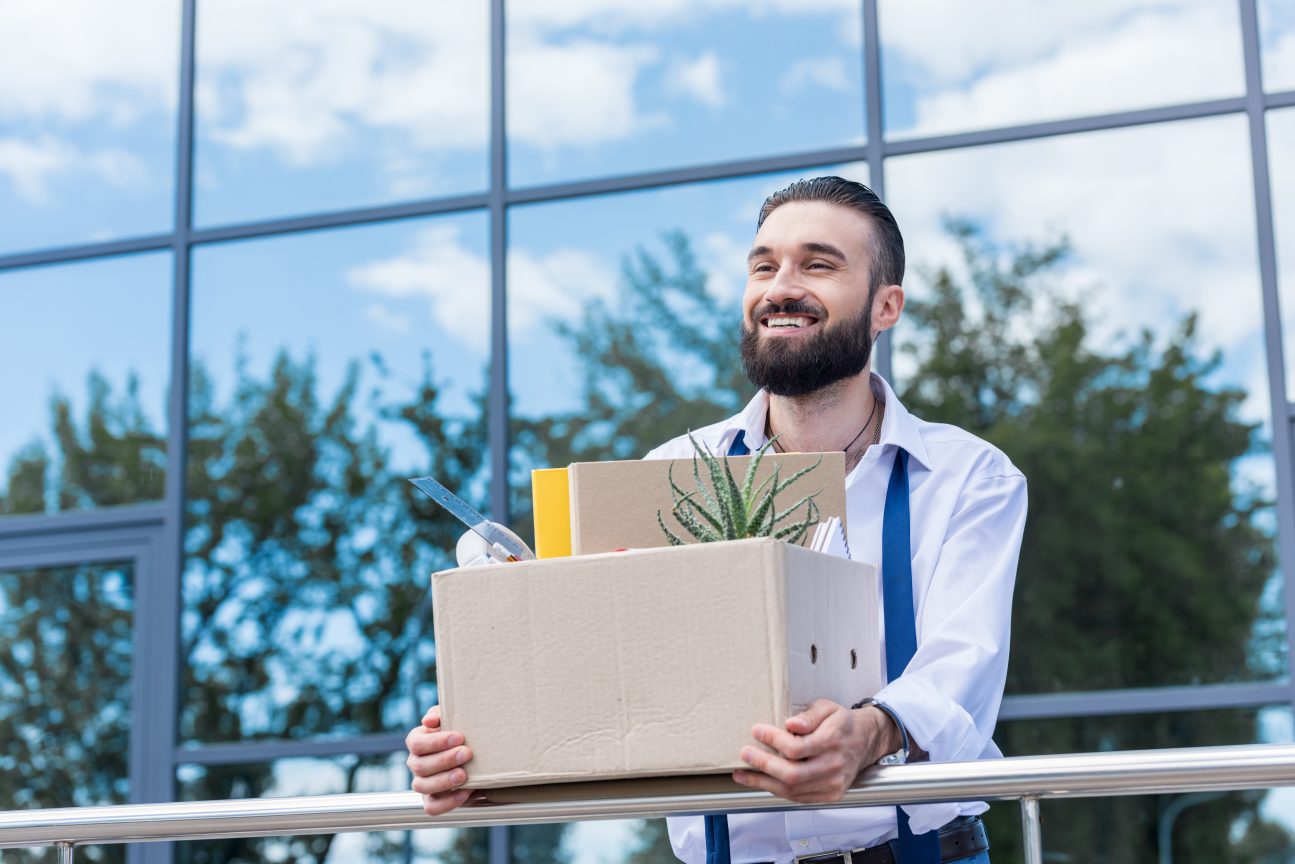 A businessman quits his job as part of the Great Resignation and smiles contently.