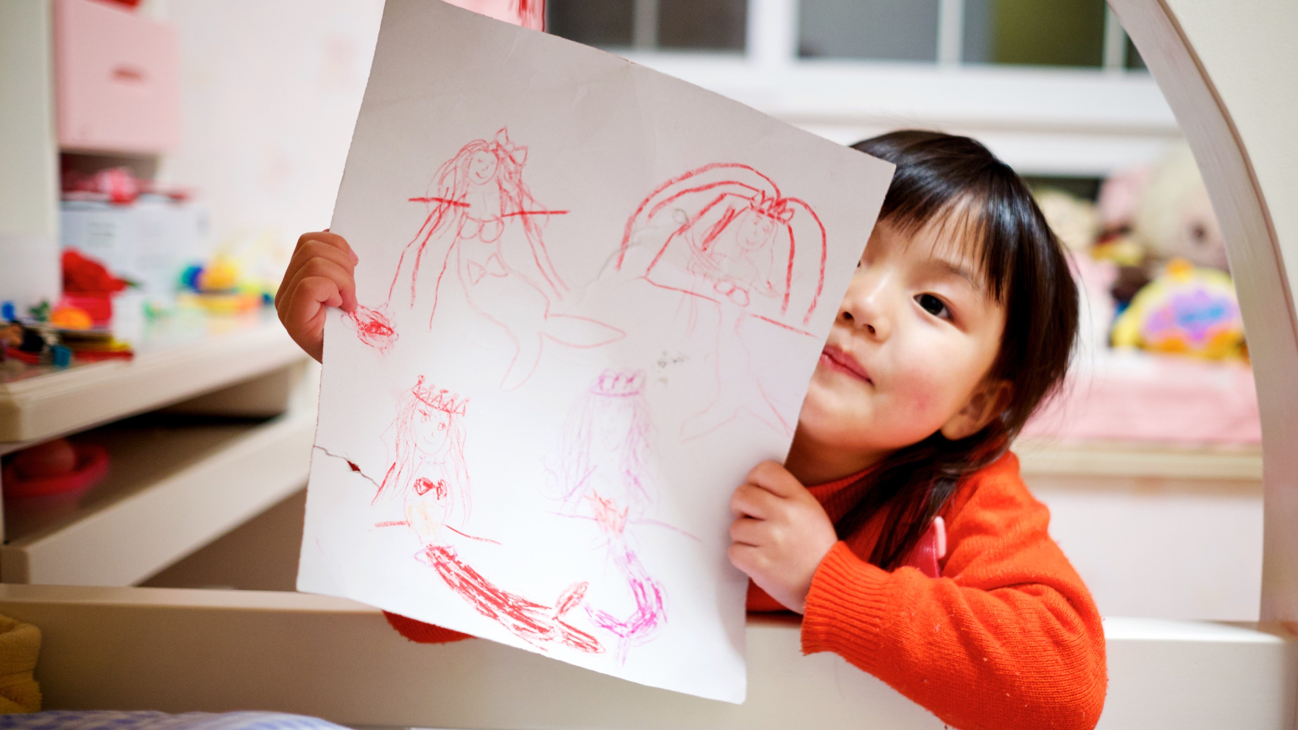 A child showing their drawing to the camera