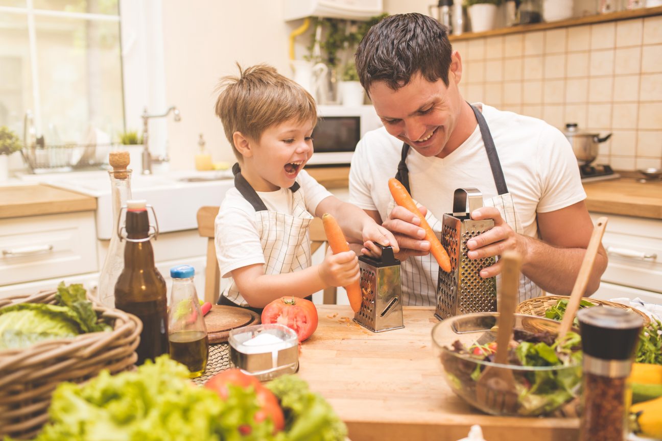 A stay-at-home dad cooking with his son