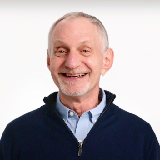 An older man smiling in front of a white background.