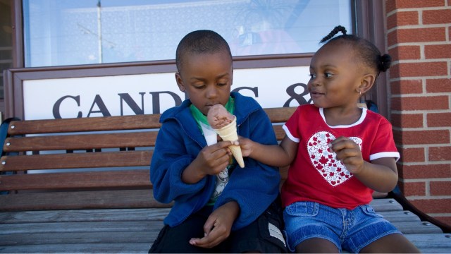 A boy and girl share an ice cream cone