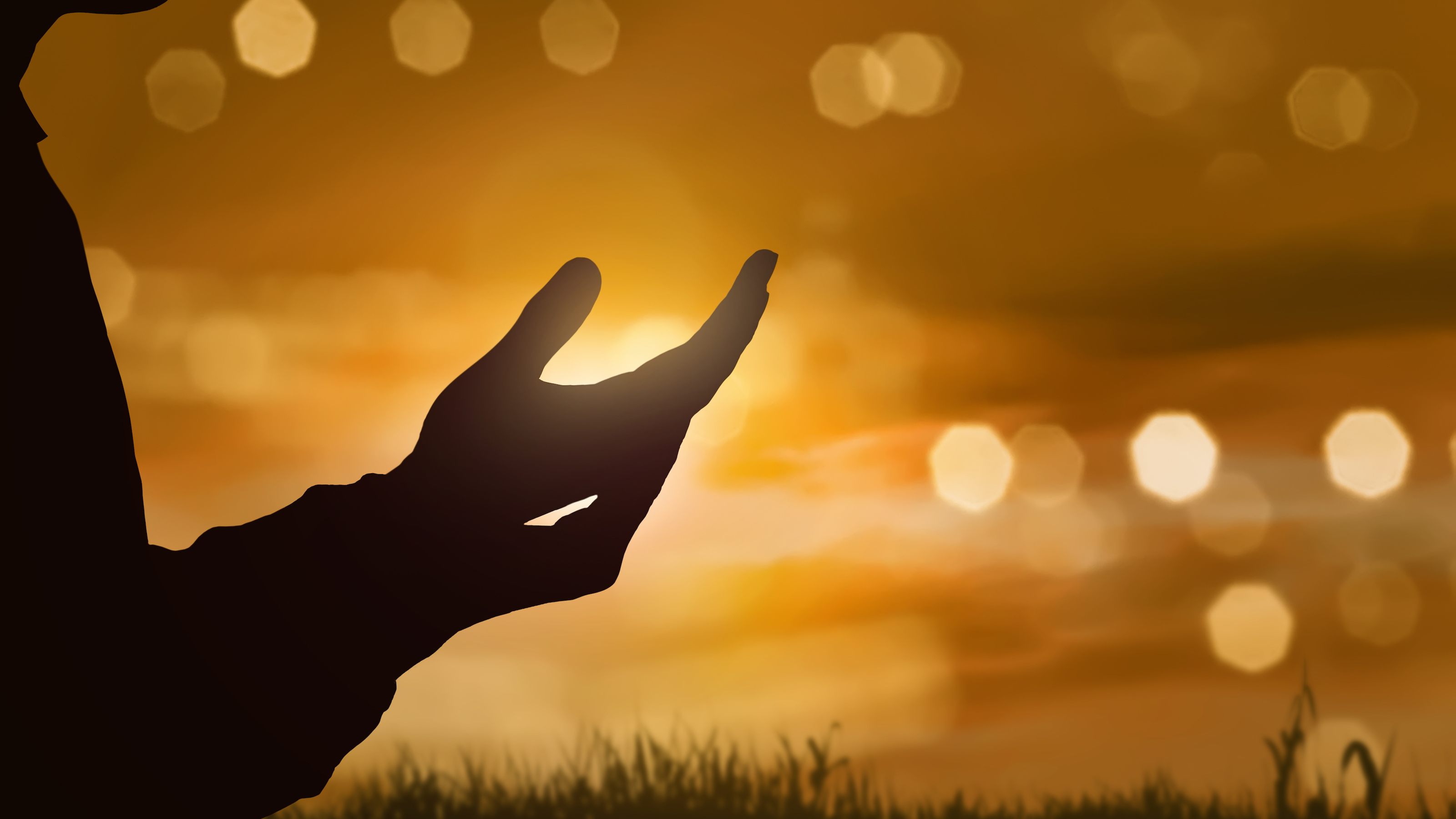 Silhouette of human hand with open palm praying to god at sunset background