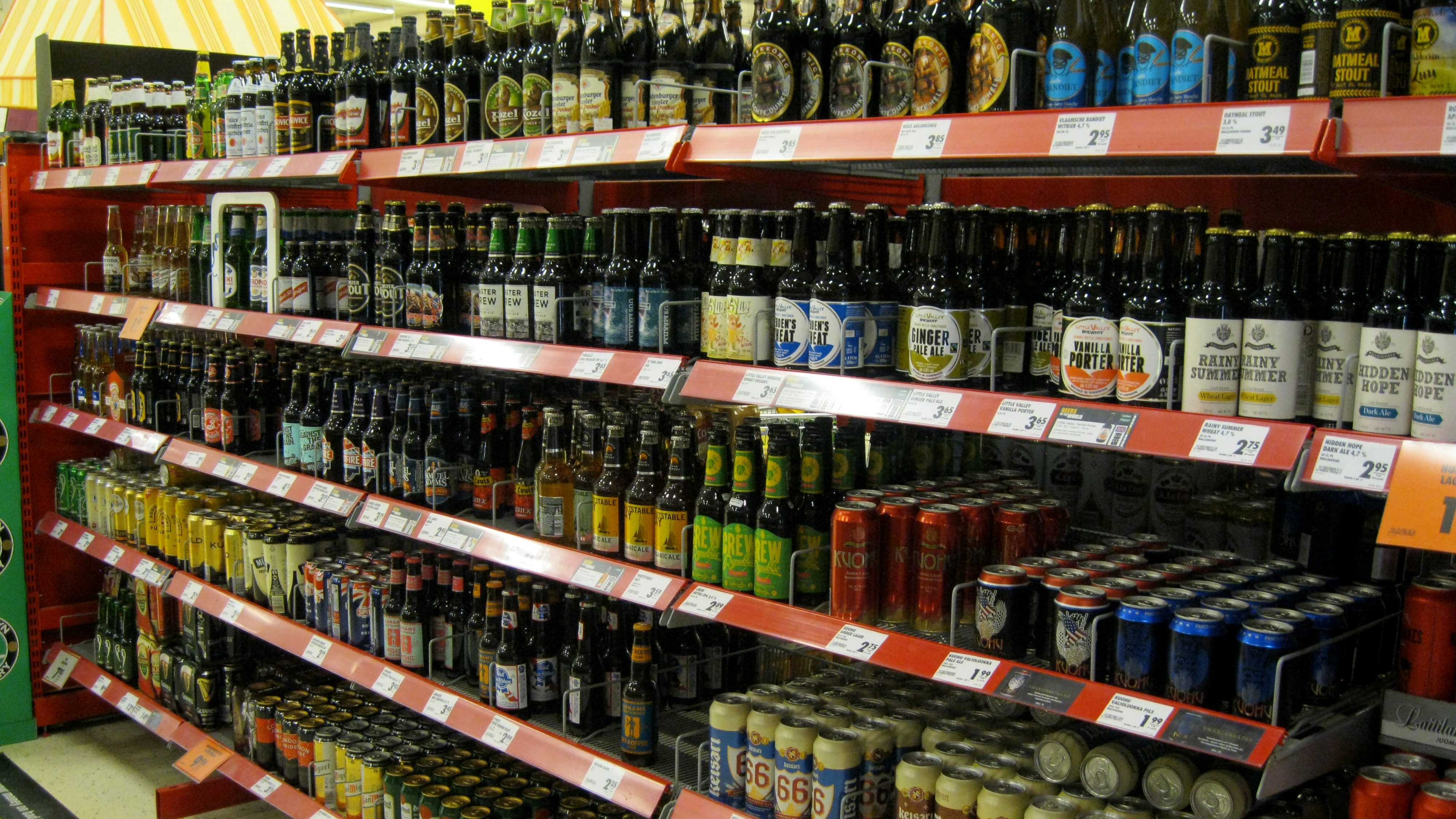 Grocery stores shelves filled with lots of bottles of beer.