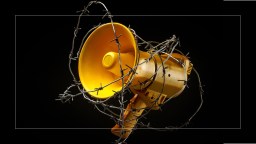a yellow bullhorn surrounded by barbed wire.
