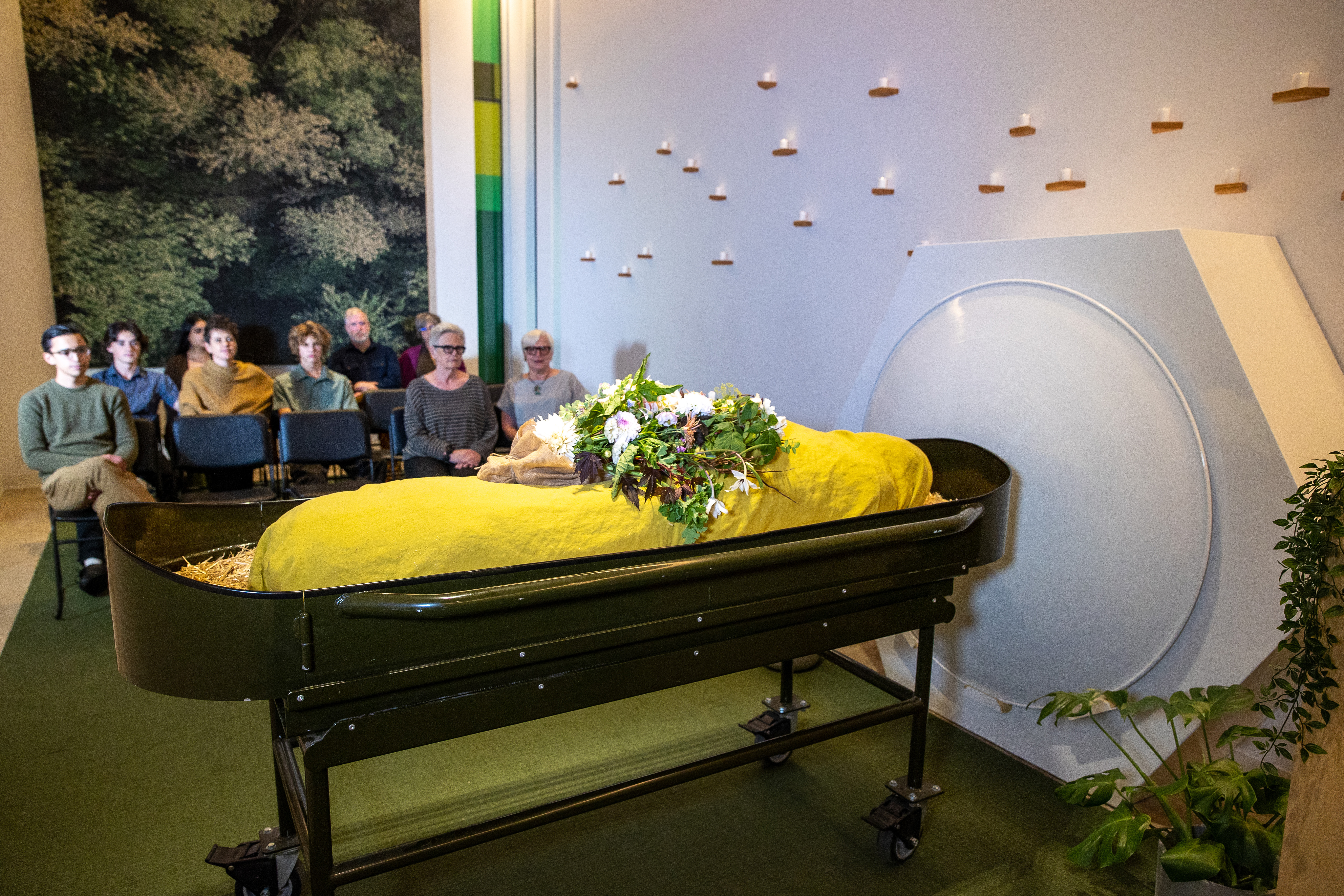 a group of people watching a man laying in a coffin