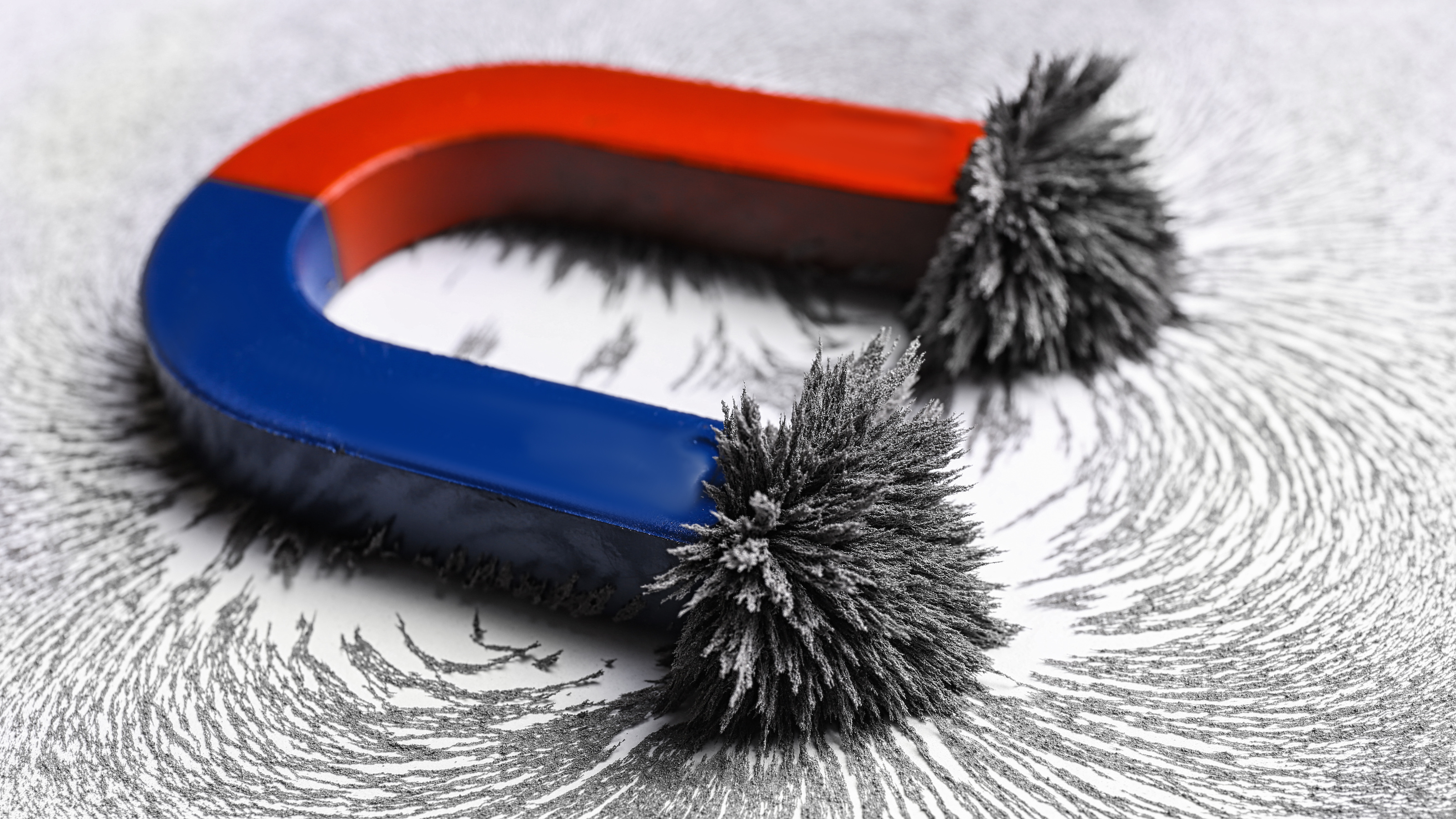 a blue and red magnet sitting on top of a white surface with iron filings