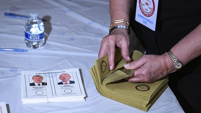 a woman is putting a voting paper in a folder.