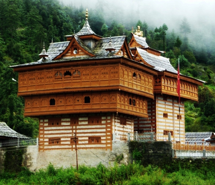 a large wooden building sitting on top of a lush green hillside.