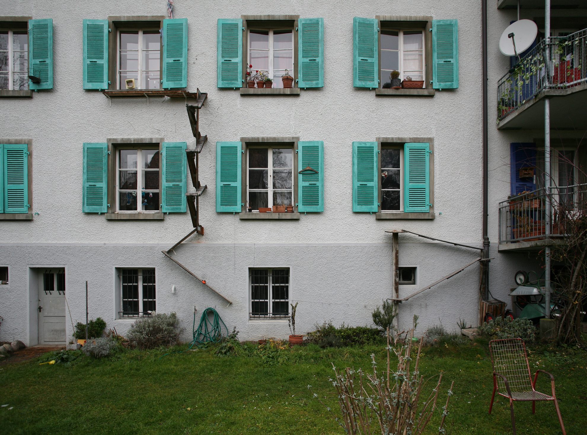 a white building with blue shutters and green shutters.