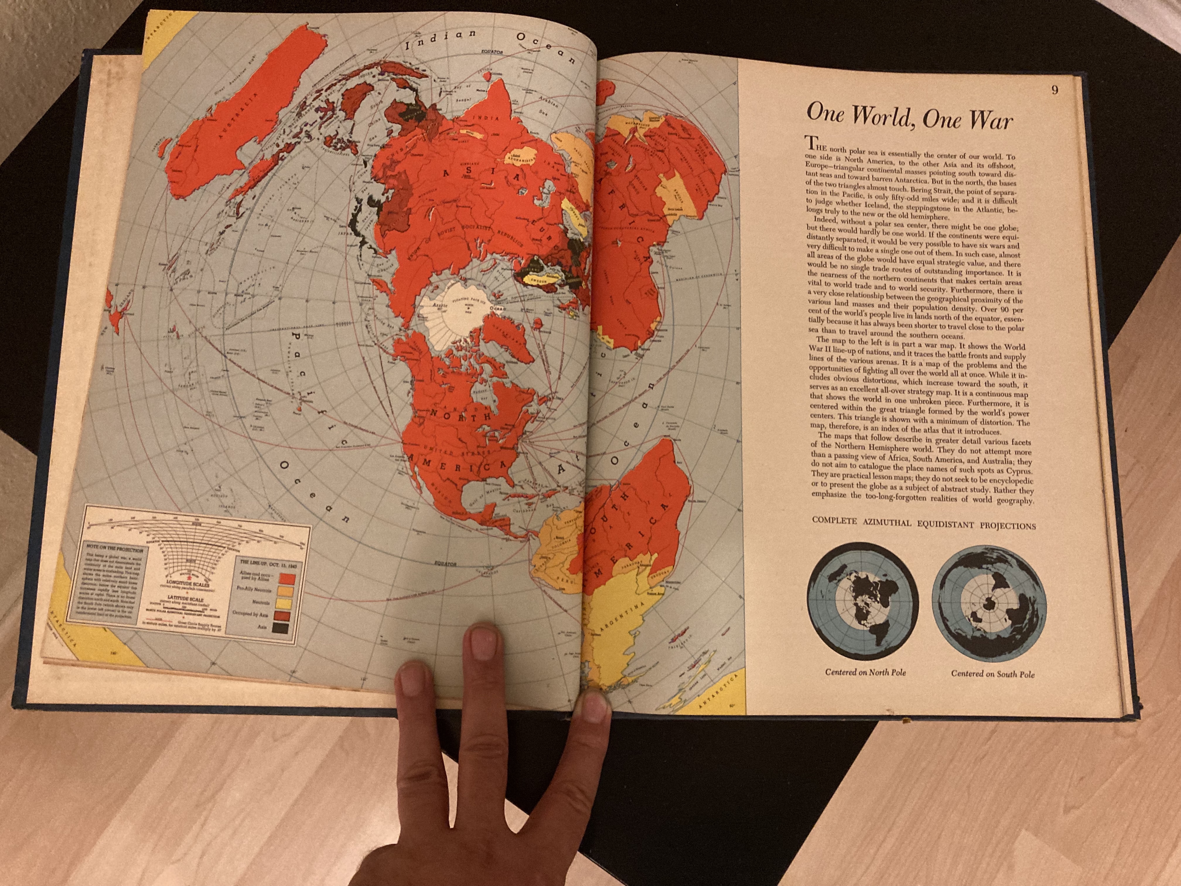 A person holding a book to a world map.