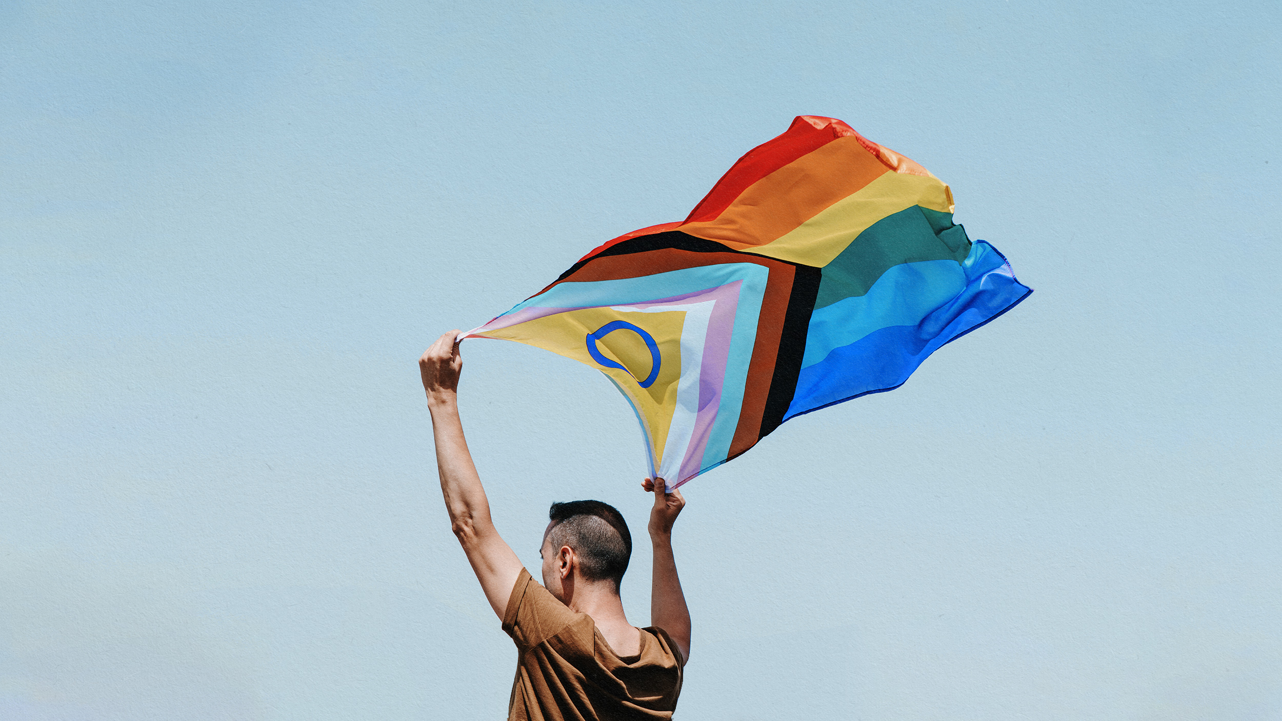 a woman holding a rainbow colored kite in the air.