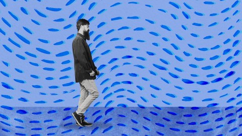 a man walking in front of a blue background.