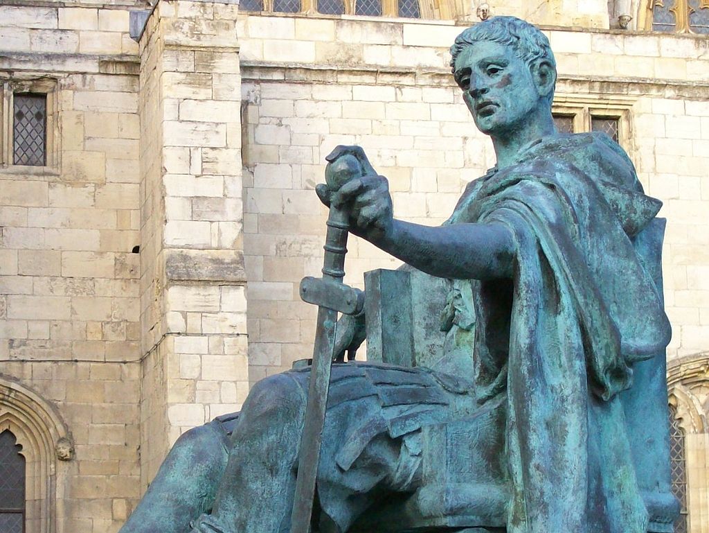 A statue of a man holding a sword in front of a cathedral.
