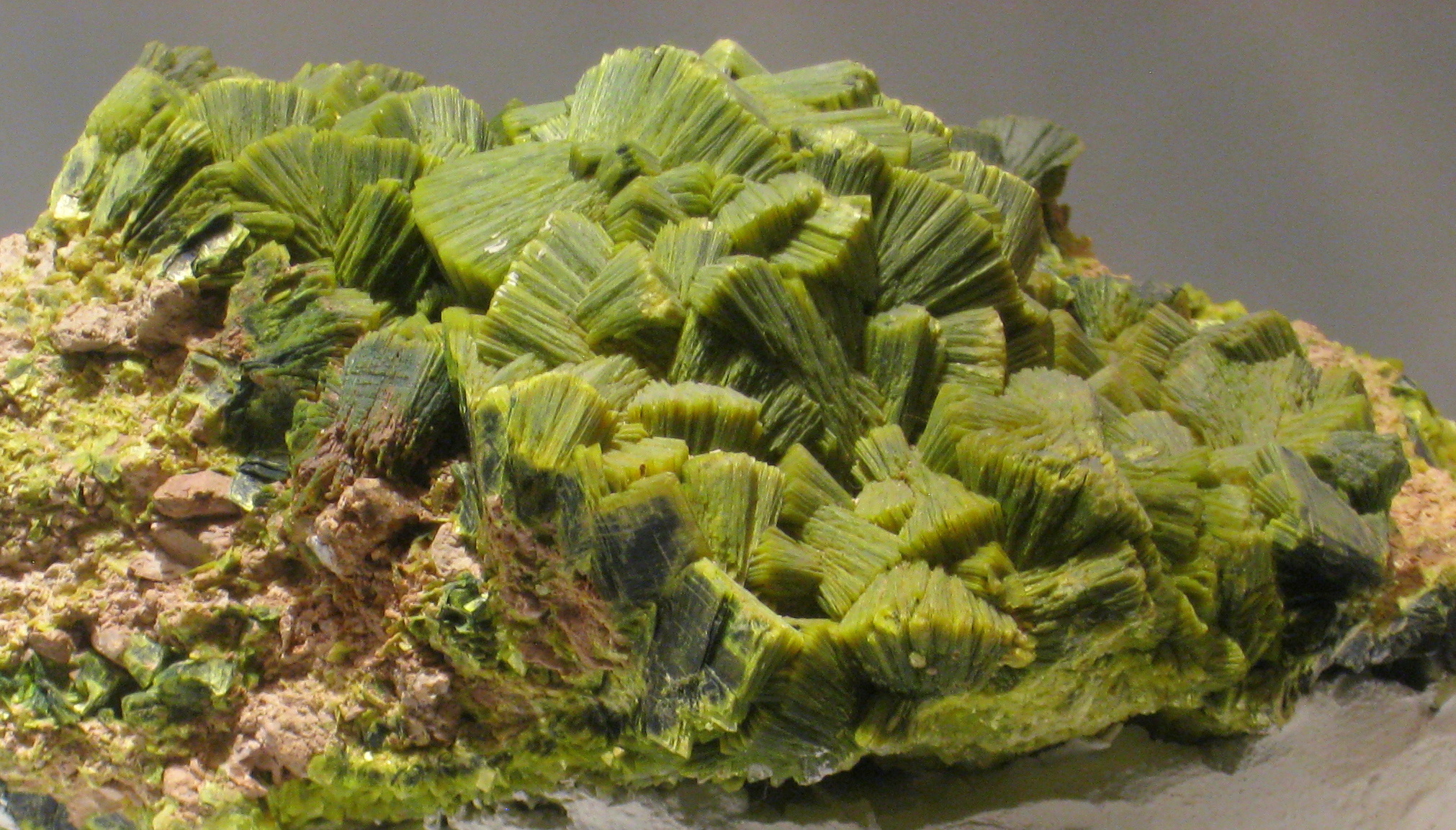 A green mineral on top of a piece of rock.