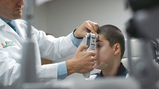 A doctor is examining a boy's eye.