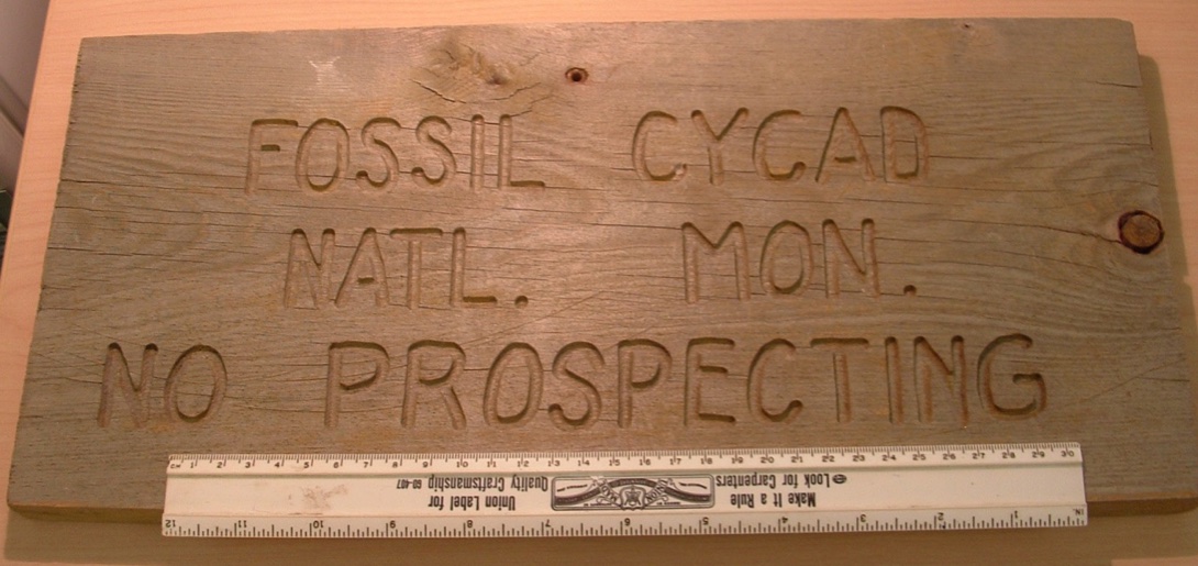 A wooden sign that reads fossil cycad nat mon no prospecting.