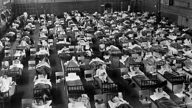 An old black and white photo of a room full of beds.