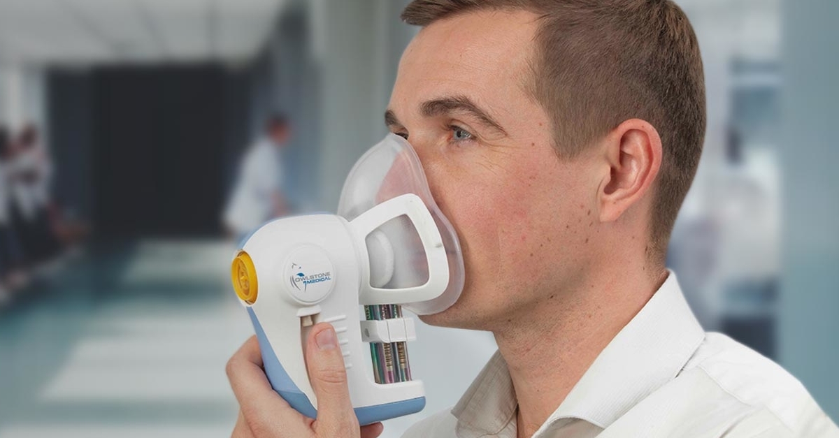 A man with liver disease is using a nebulizer in a hospital.