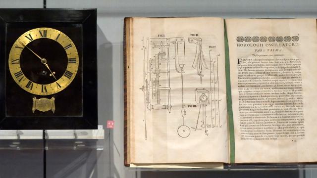 A clock, believed to be the first in America, showcased beside a book.