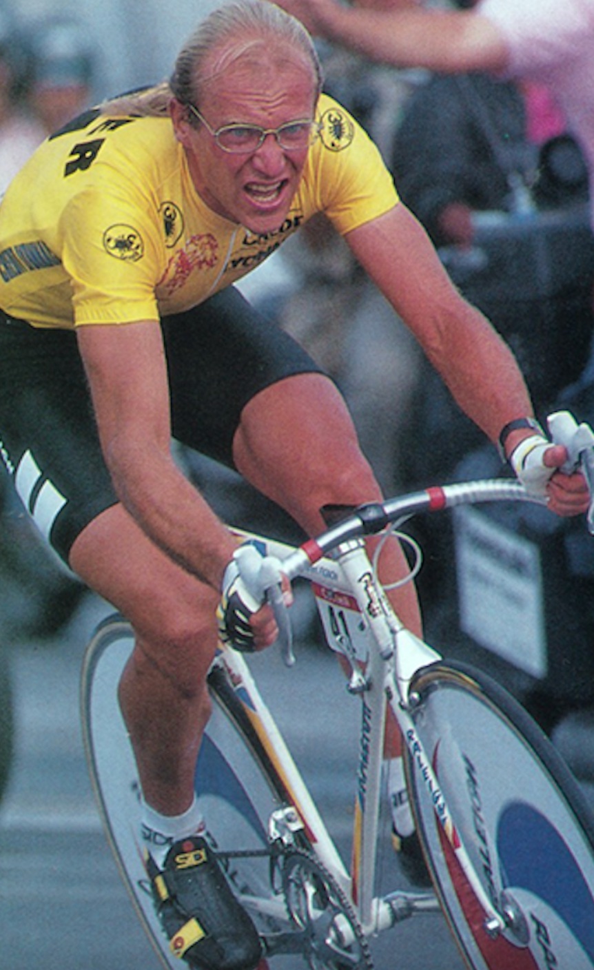 A man riding a bike in front of a crowd.