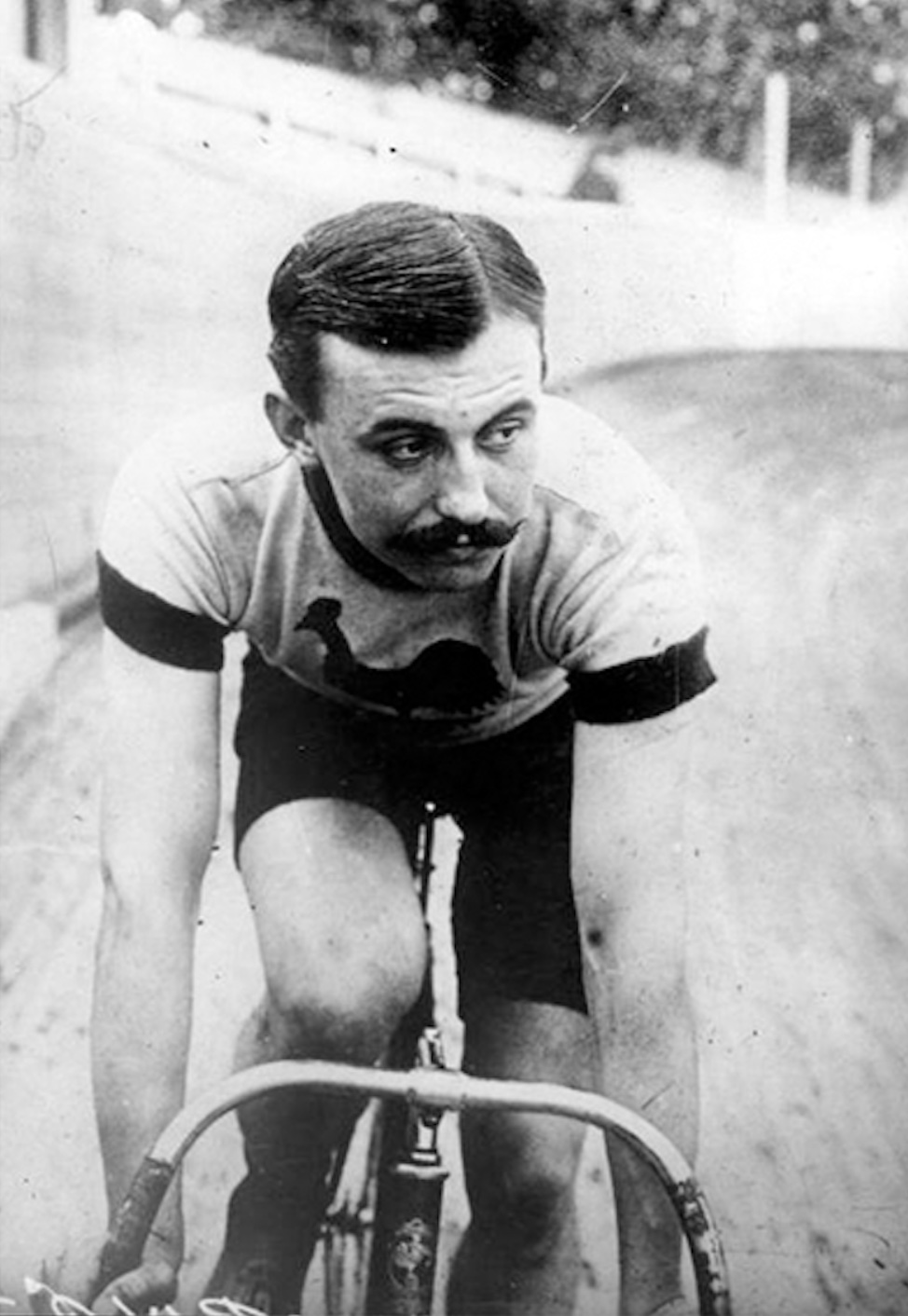 An old photo of a man riding a bicycle.
