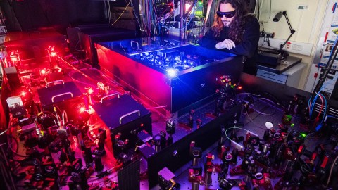 A man exploring quantum computing in a room with red lights.