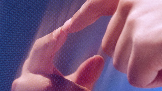 A person's hand is interacting with a blue screen.