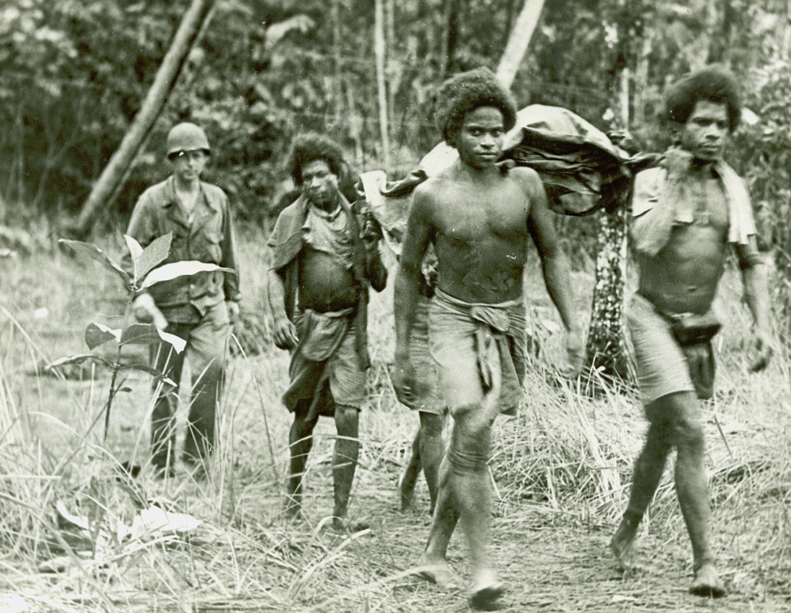 A group of men walking through a forest in Papua New Guinea.