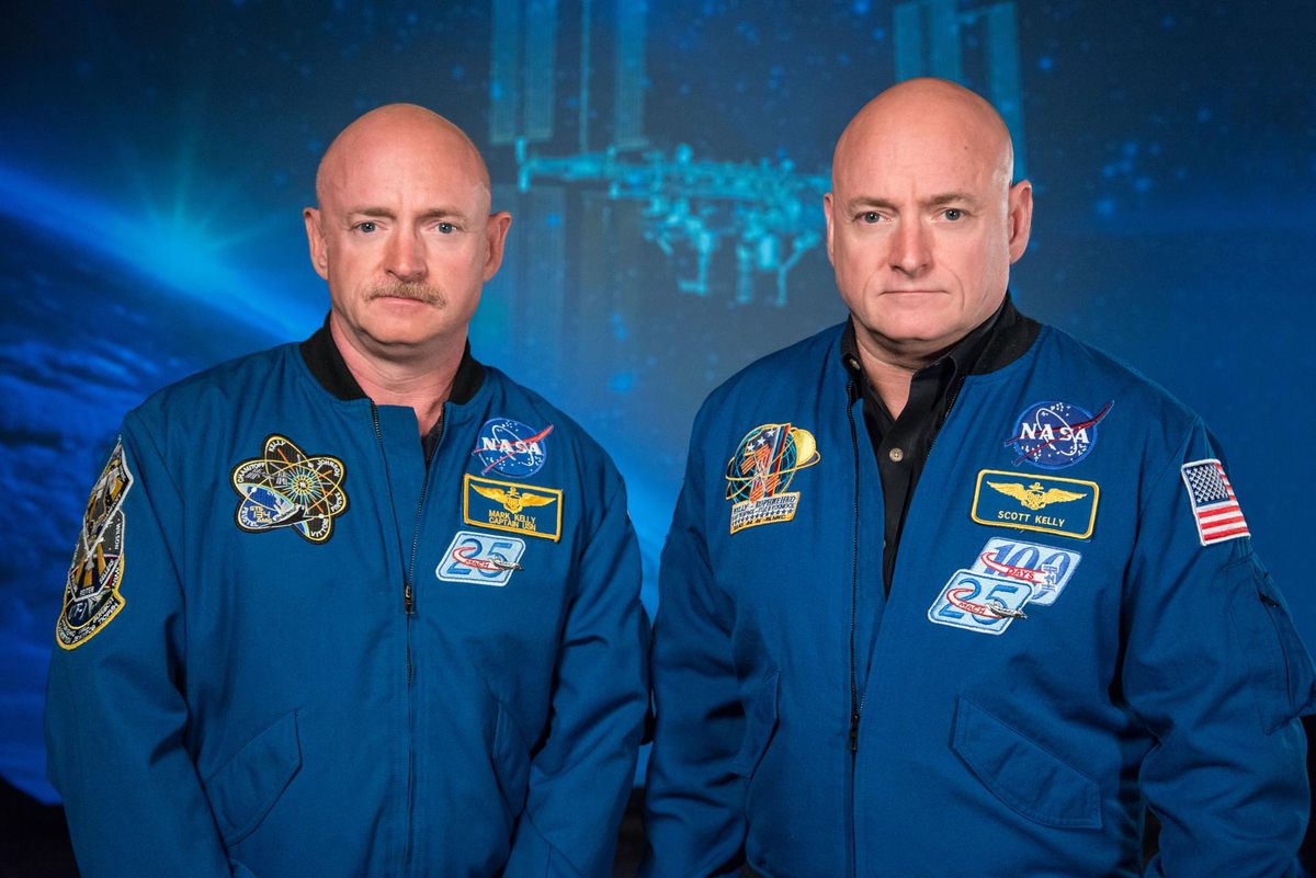 Two men in blue space suits standing next to each other.