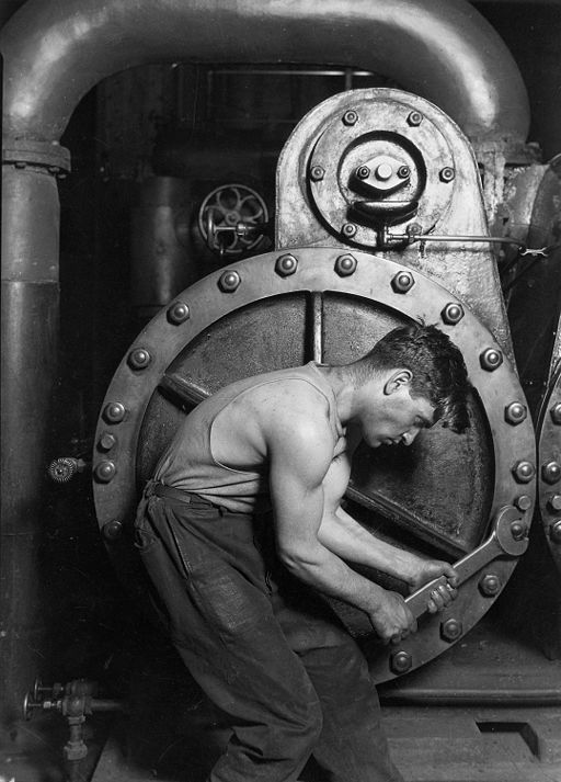 An old black and white photo of a man working on a steam engine.