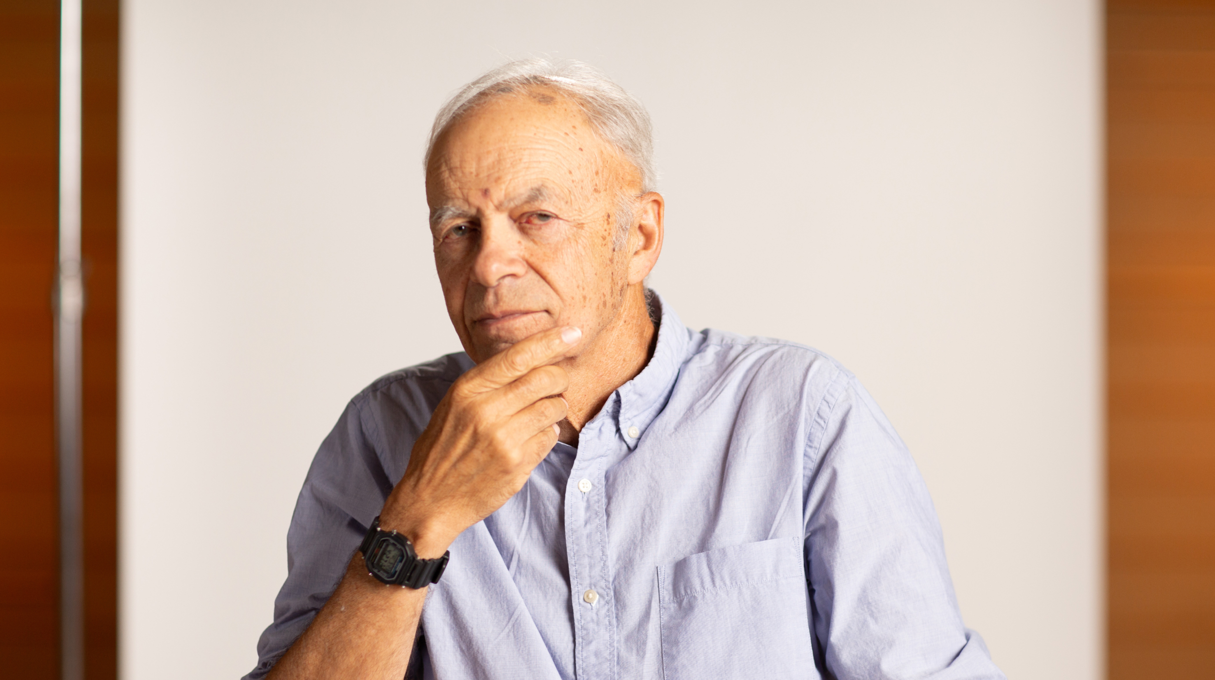 An older man pondering with his hand on his chin, contemplating effective altruism.