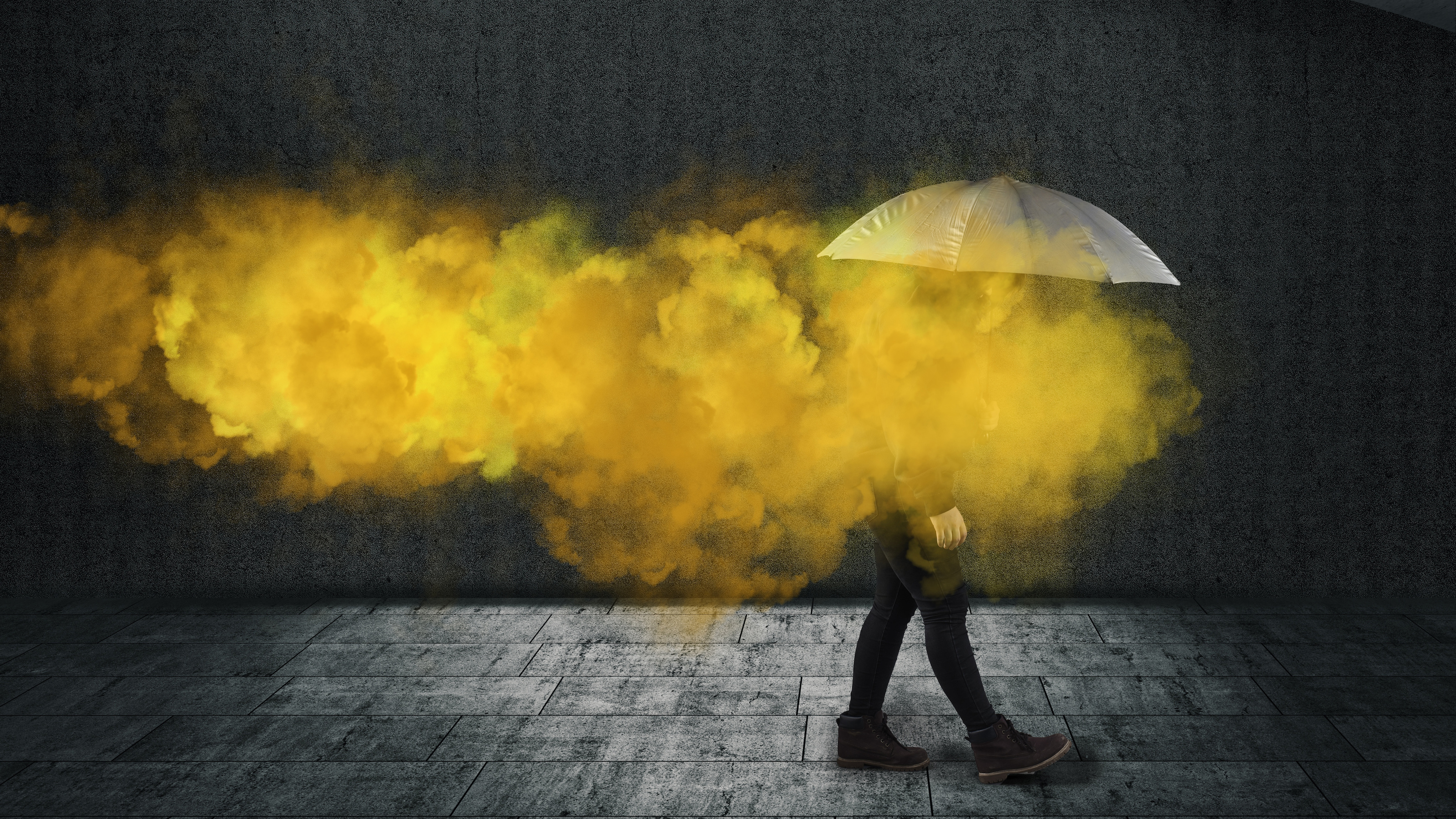 A person is walking with an umbrella in front of a yellow smoke.