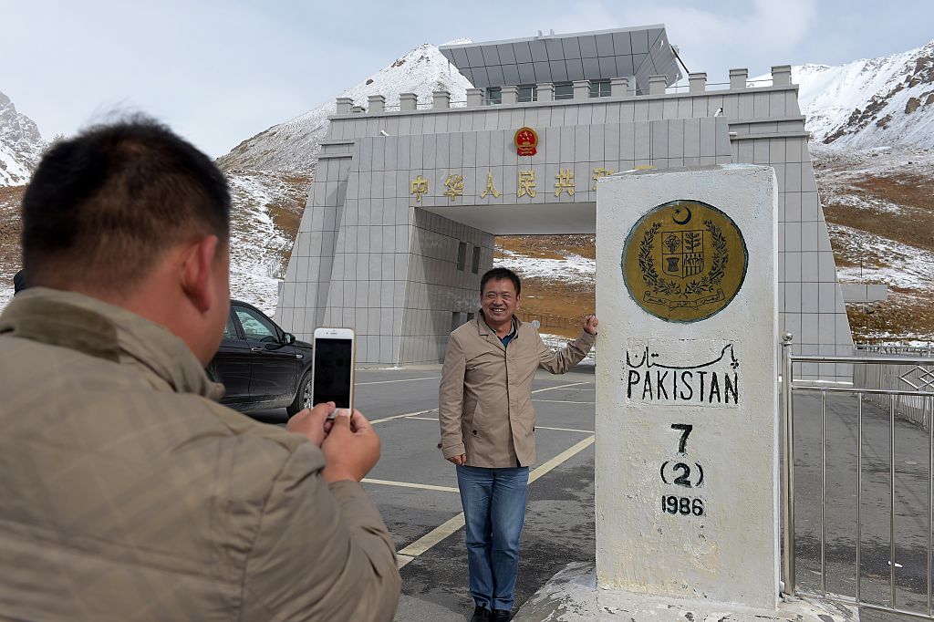 A man takes a picture of a sign in front of a mountain.
