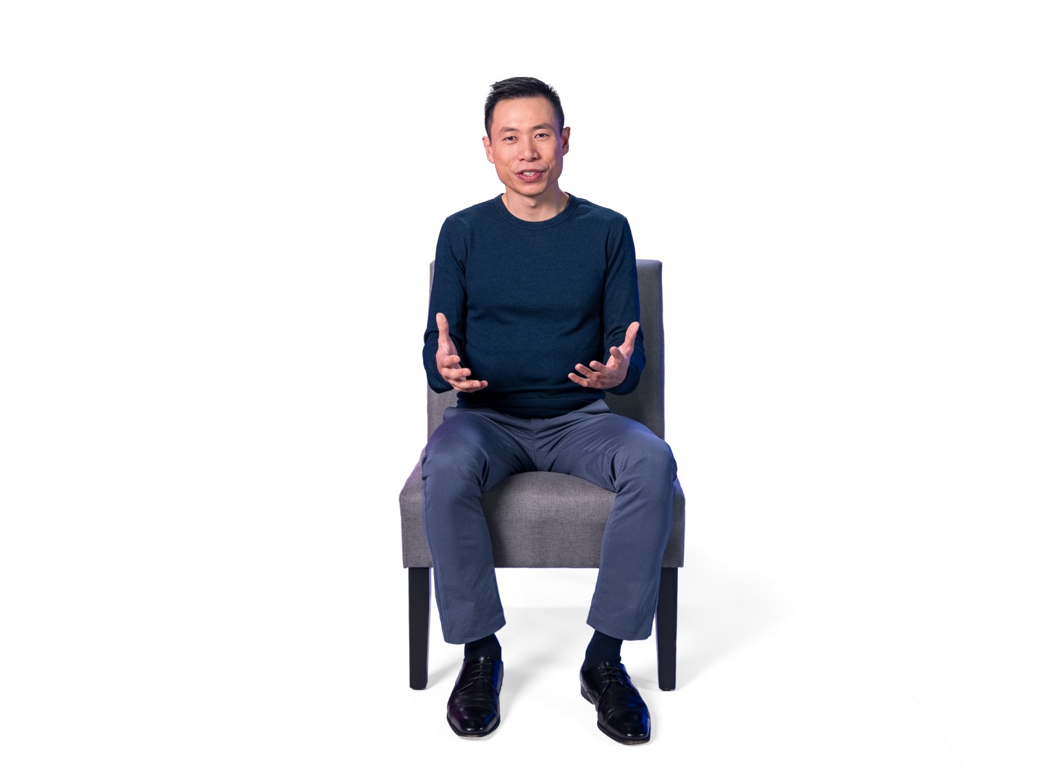 A man sitting on a chair with his hands in his pockets.