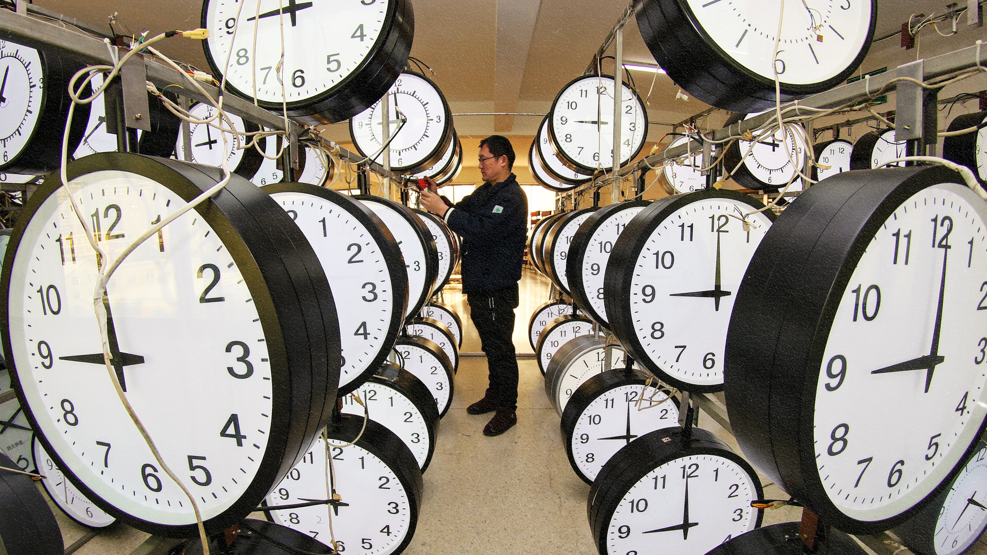 A man surrounded by clocks in a room.