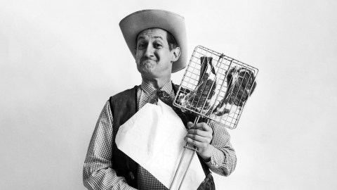 A man in a cowboy hat holding a chicken.