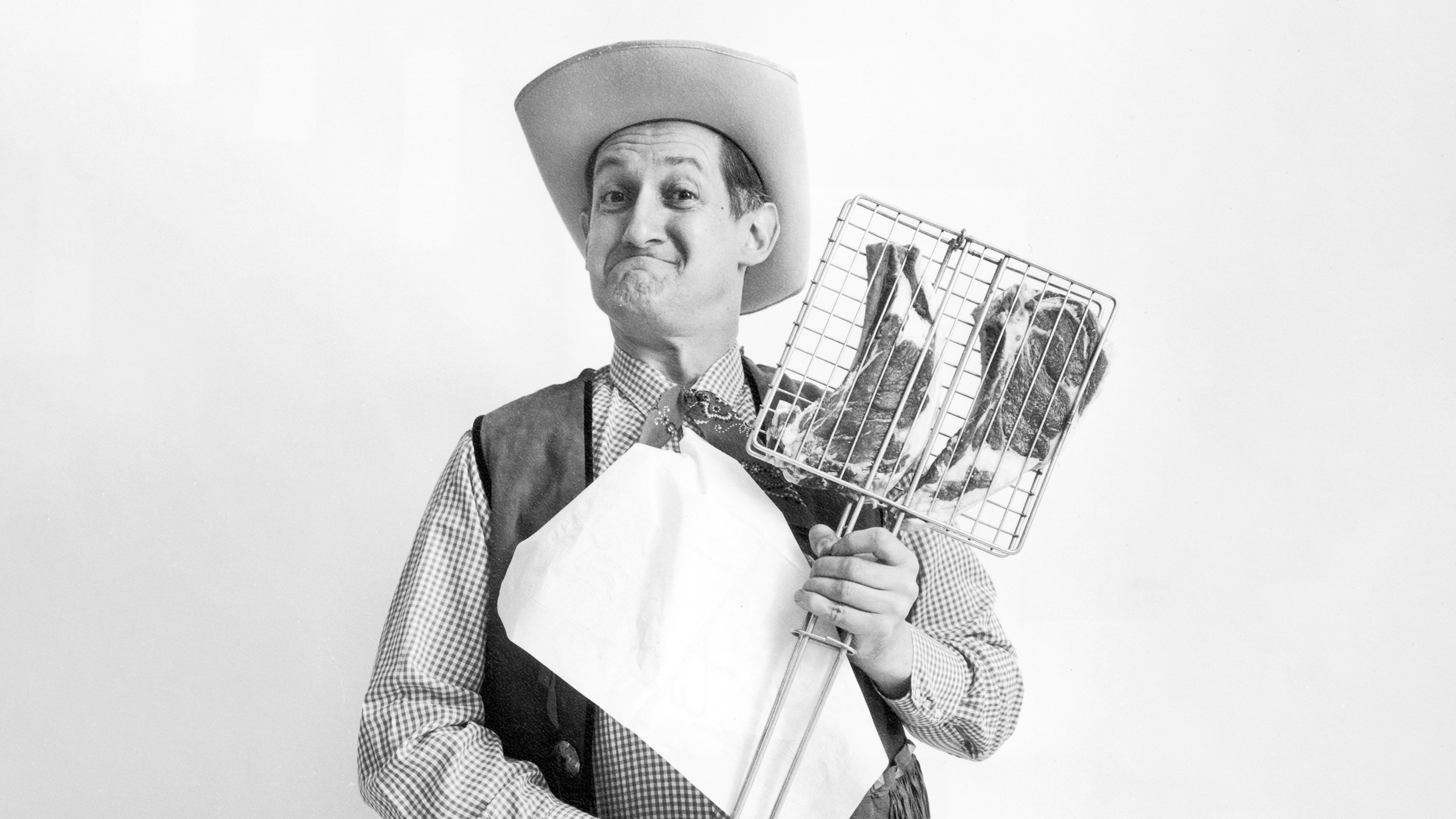 A man in a cowboy hat holding a chicken in a basket.