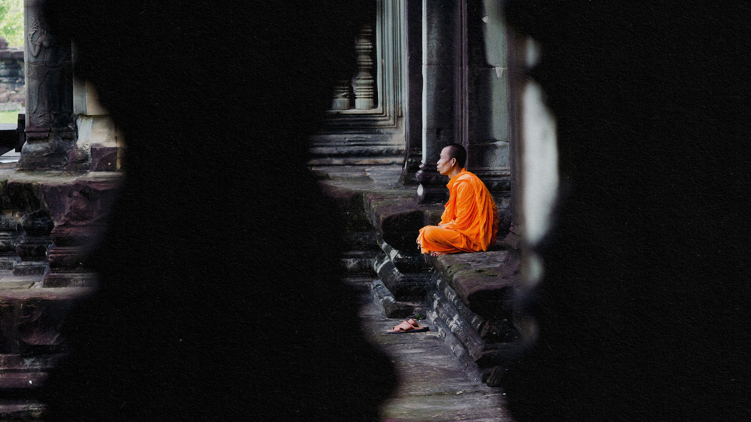 An orange-robed monk practicing mindfulness on a stone wall.