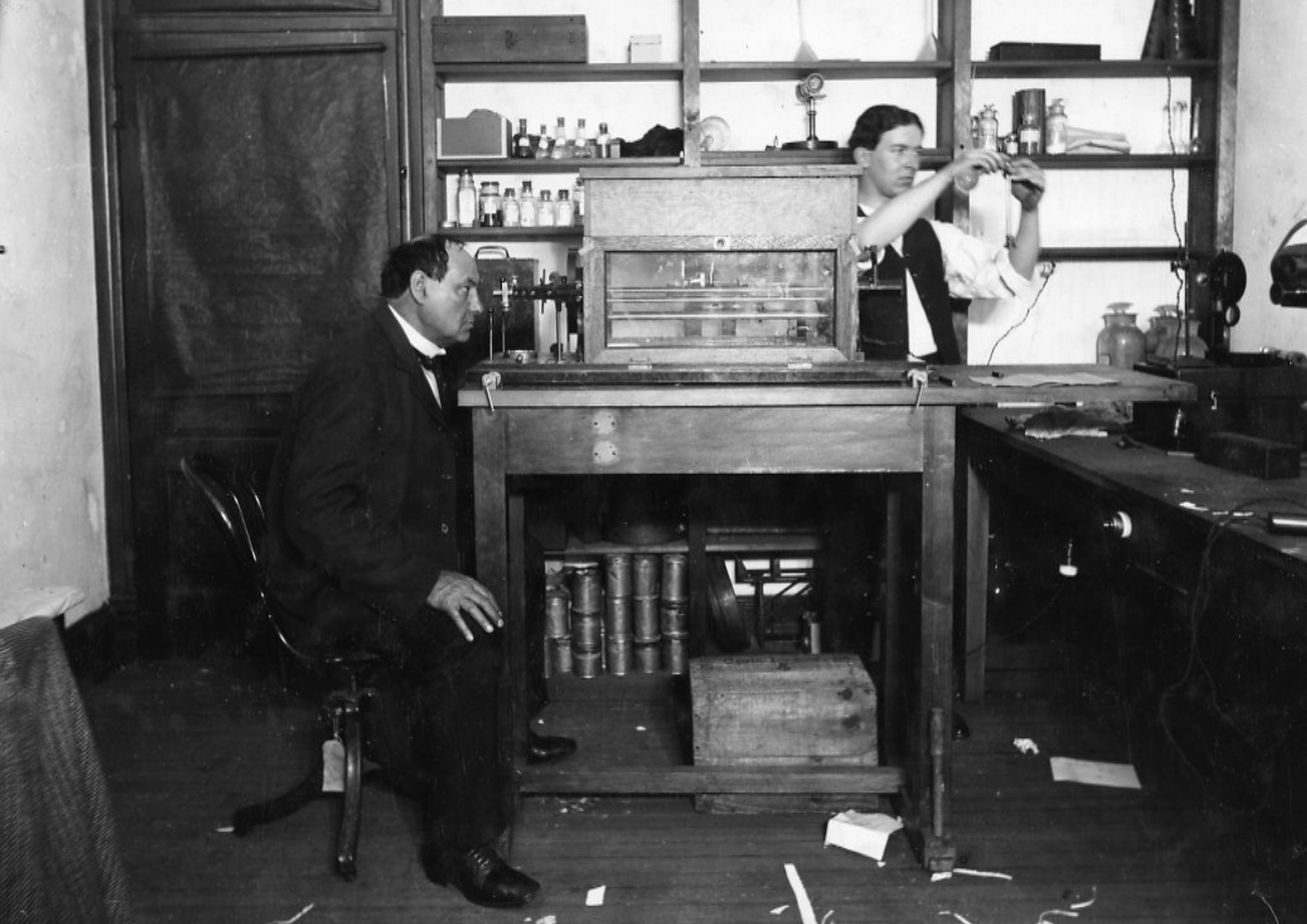 A man and woman sitting at a desk in a room.