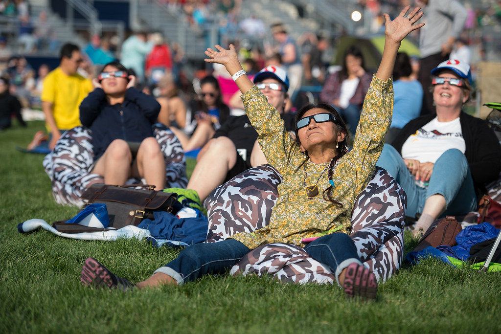A group of people engaged in eclipse activities on the grass.