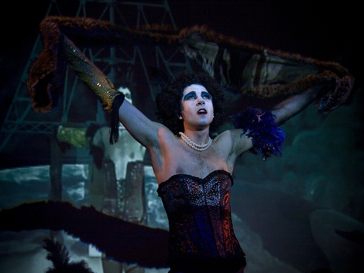 A woman in a corset on stage with her arms outstretched.