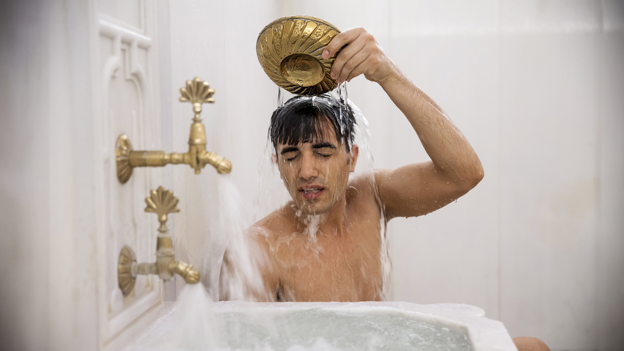 A man is taking a bath in a Thermae Romae-style bathtub.