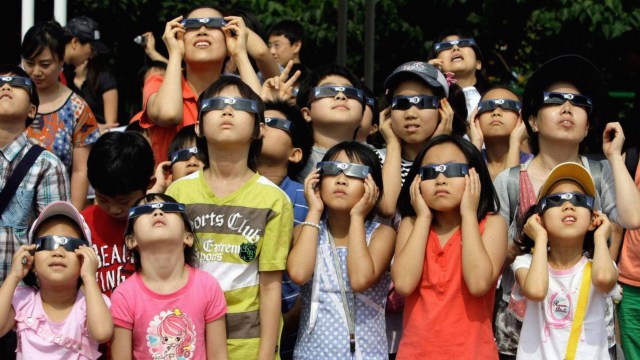 A group of children engaging in eclipse activities by wearing sunglasses and looking at the sun.