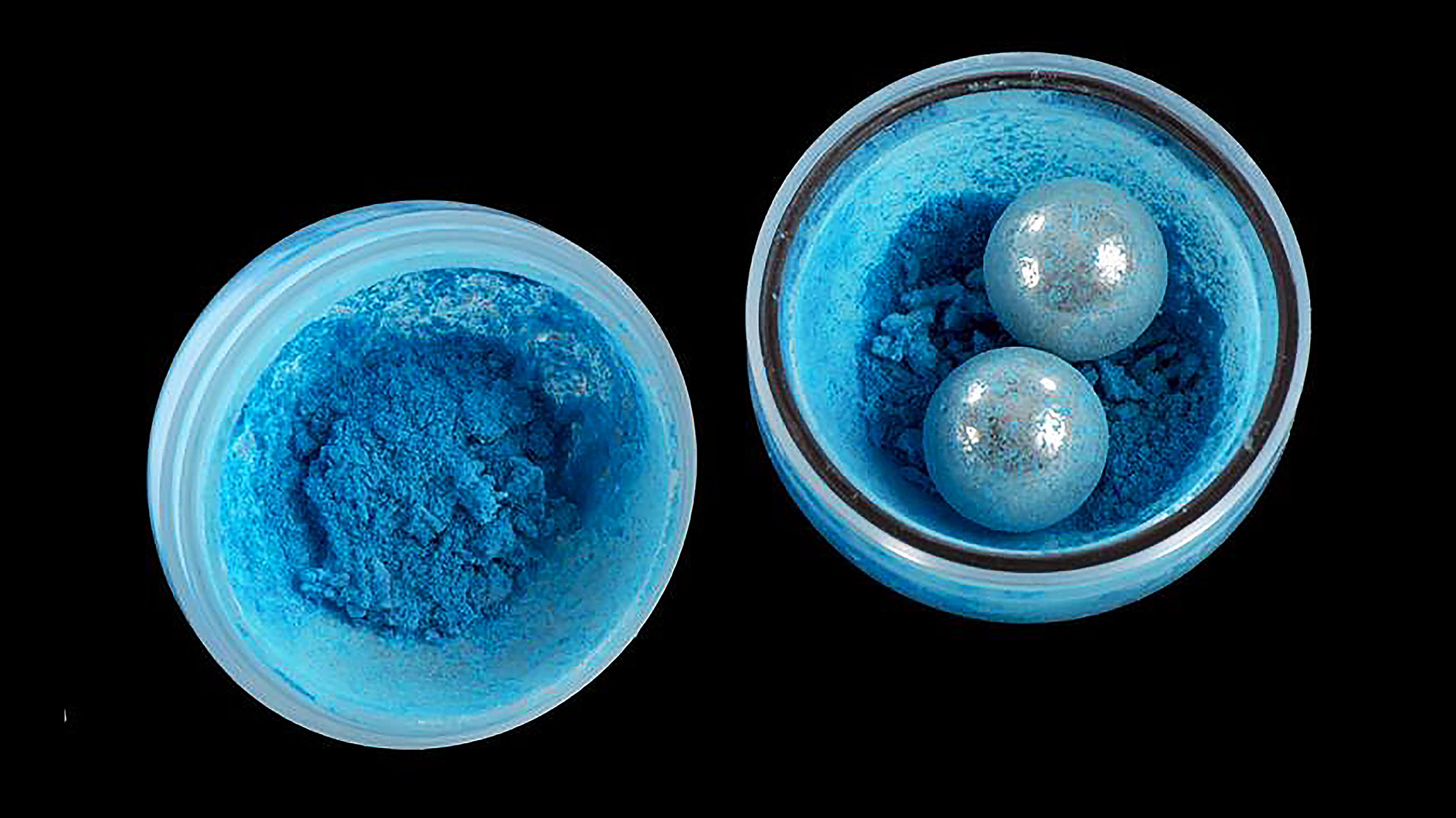 Two blue powders undergoing mechanochemistry in a bowl on a black background.