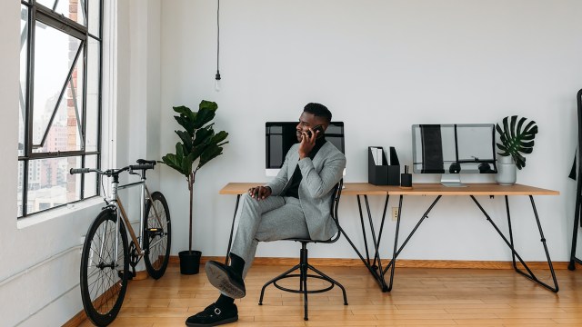 A black man, an AI specialist, sitting at a desk in a modern office while brainstorming innovative business ideas.